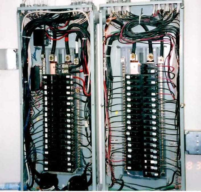 Two open breaker panels with full circuit banks and dressed conductors