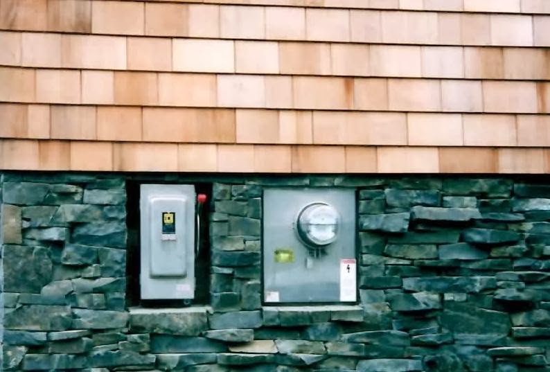 Meter base and safety disconnect set into a stone and cedar shingle wall